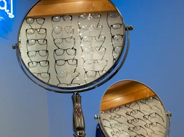 eyeglass frames in a display case seen as a reflection in two circular mirrors